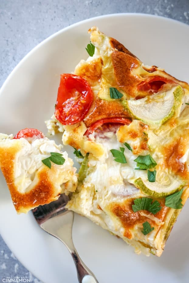 A piece of baked frittata in a white plate with a fork