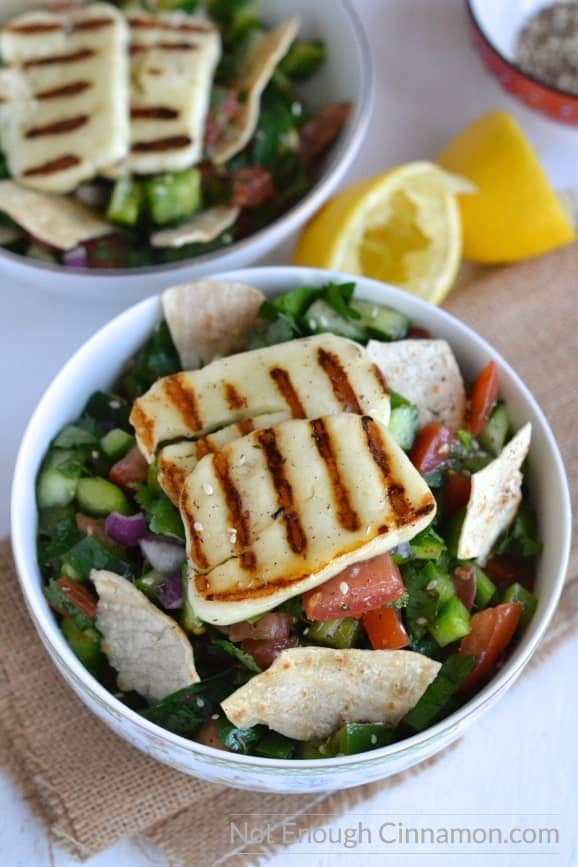 Close-up of Fattoush Salad in a bowl topped with grilled halloumi cheese and tortilla chips 