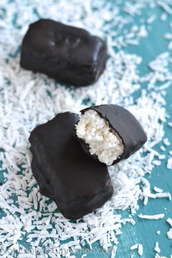 close up of Easy Homemade Vegan and Paleo Bounty Bars on a blue tabletop surrounded by shredded coconut