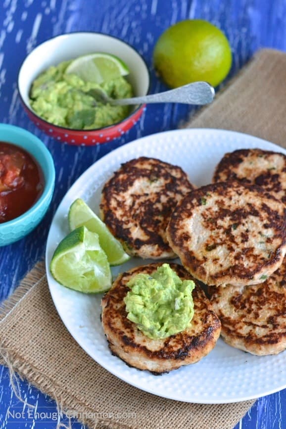 Paleo and gluten-free Mexican chicken patties arranged on a white plate with guacamole and salsa und the side