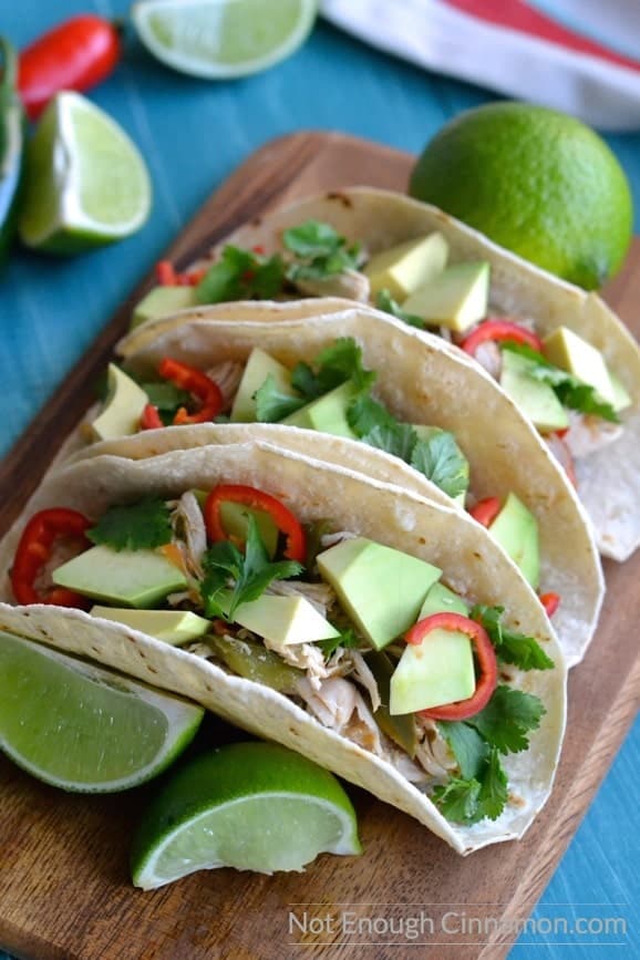 close-up of healthy gluten-free shredded chicken tacos with avocado cubes, red chili slices and fresh cilantro