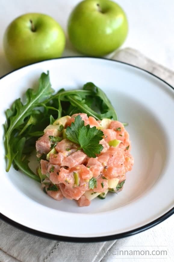 side view of Salmon Tartare with apples and cilantro with a side of fresh arugula