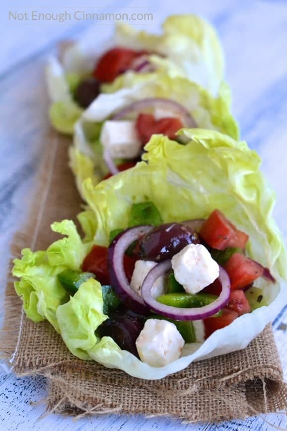 three vegetarian lettuce cups filled with Greek Salad lines up on a piece of cloth