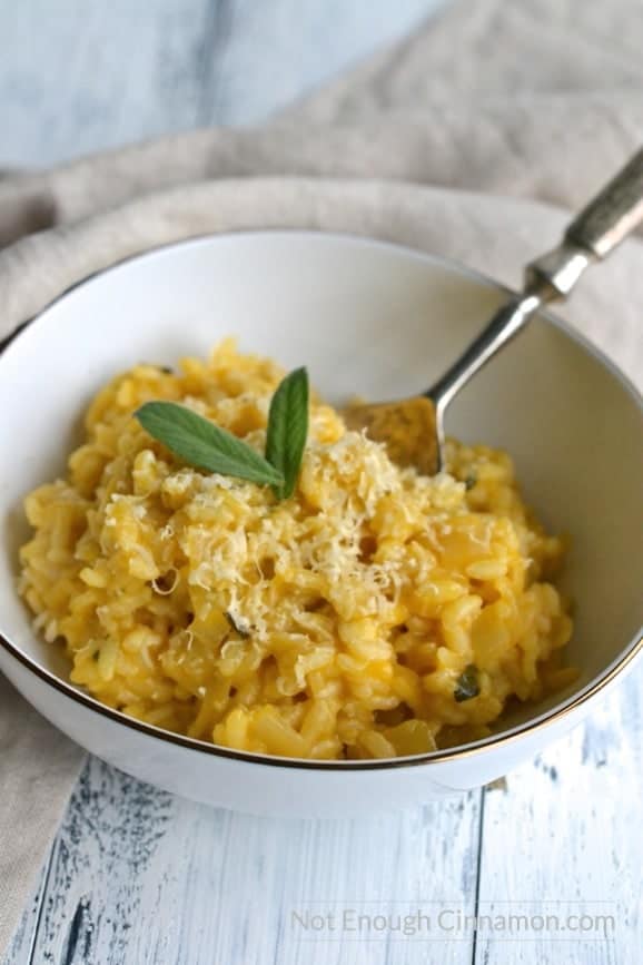 close-up of a bowl of easy pumpkin risotto topped with grated parmesan and small sage leaves 