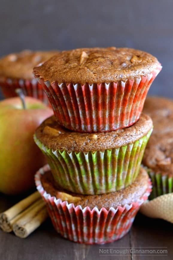 three healthy apple spice muffins stacked on top of each other with some apples and a cinnamon stick on the side