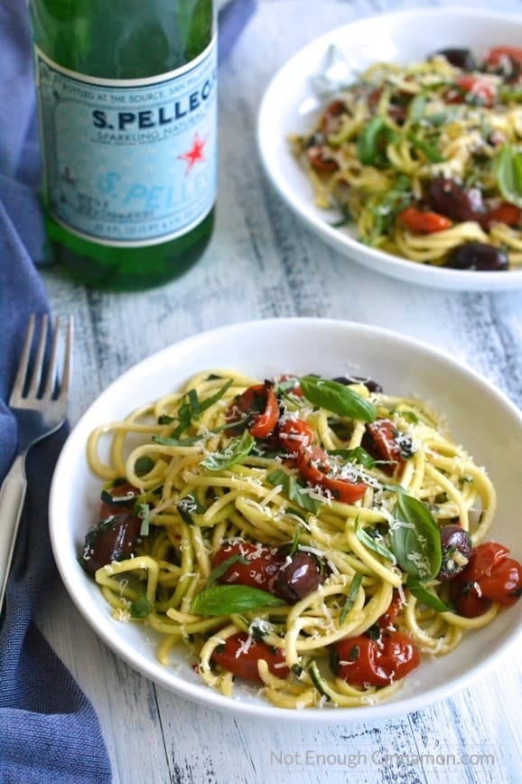 two bowls of Spiralized Zucchini Pasta (aka. Zoodles) alla Puttanesca sprinkled with fresh basil and parmesan