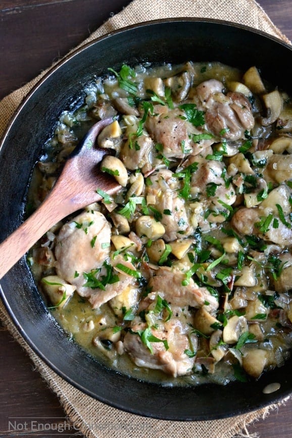 close-up of a skillet with chicken with mushrooms with plenty of gravy sprinkled with freshly chopped parsley