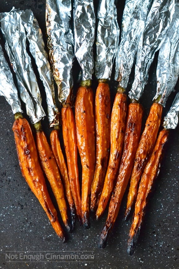 balsamic roasted carrots fresh out of the oven with aluminum foil still wrapped around the greens