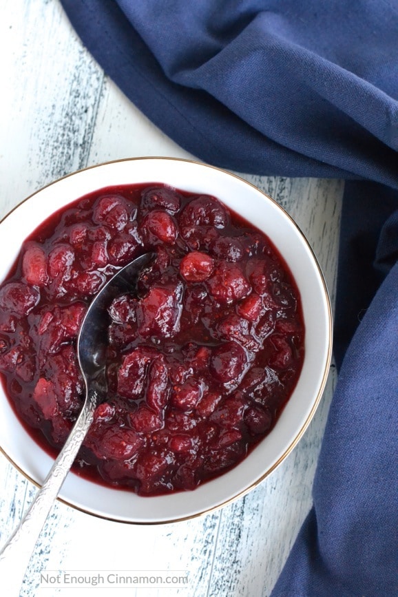 overhead shot of homemade cranberry sauce with orange juice in a white bowl with a blue napkin on the side