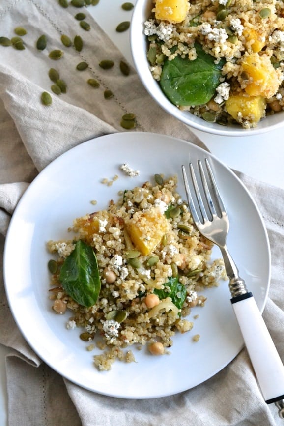 overhead shot of a plate of quinoa salad with roasted acorn squash, spinach chickpeas and crumbled goat cheese 