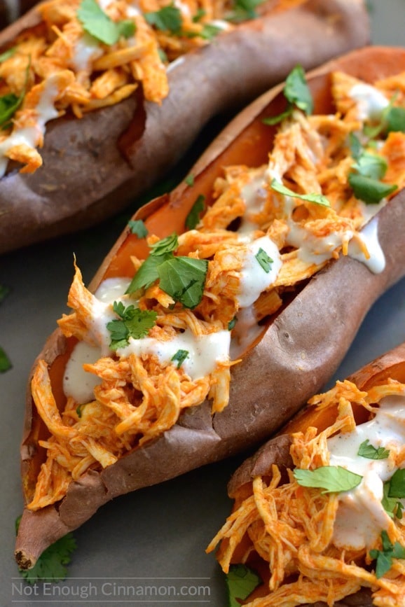 close-up of a baked sweet potatoes loaded with shredded buffalo chicken and drizzled with skinny blue cheese sauce! 