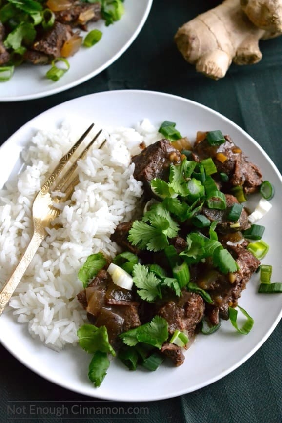 overhead shot of a serving of slow cooker orange ginger beef with rice on the side and some fresh ginger in the background