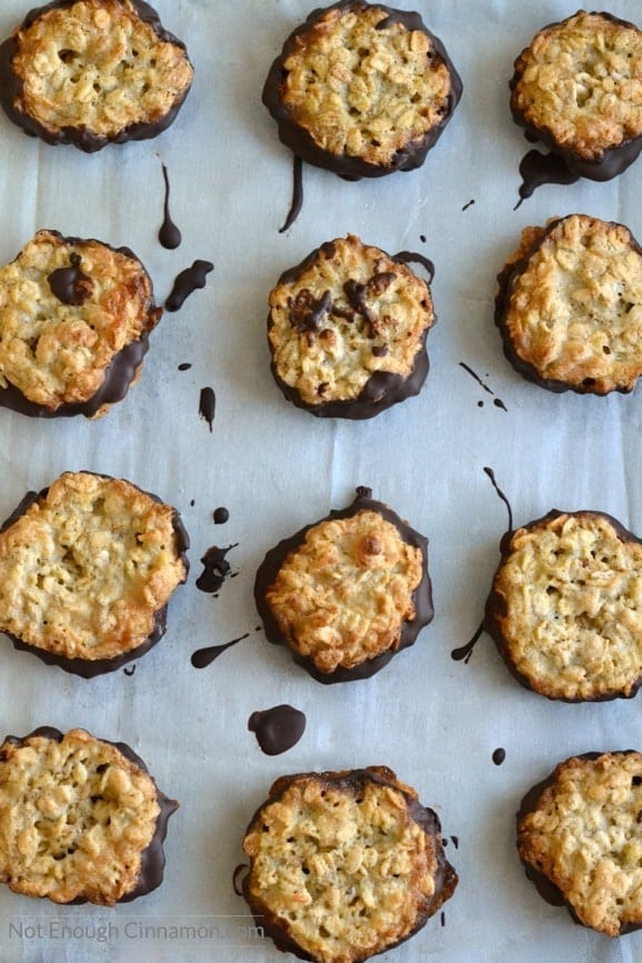 Ikea Crispy Oatmeal Cookies dipped into chocolate cooling on a parchment paper-lined tray