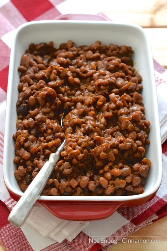 overhead shot of a red casserole filled with homemade slow cooker baked beans with molasses, bacon and brown sugar