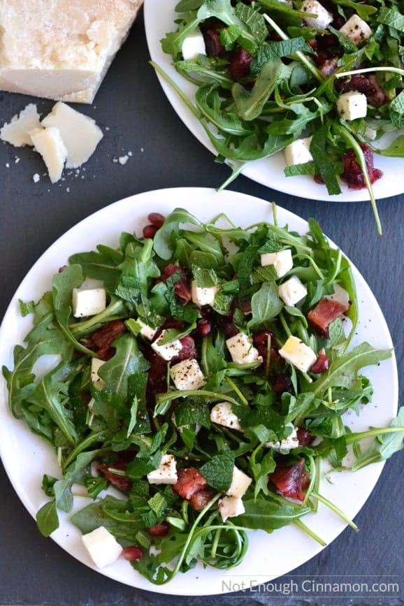 two plates of Blood Orange, Mozzarella and Arugula Salad with a wedge of parmesan cheese on the side