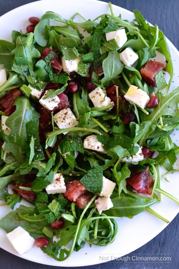 overhead shot of Blood Orange, Mozzarella and Arugula Salad with lemon dressing on a white plate