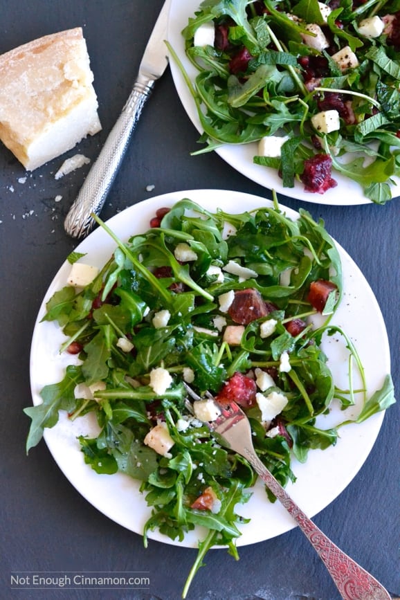 two plates of Blood Orange, Mozzarella and Arugula Salad with pomegranate arils and mint leaves