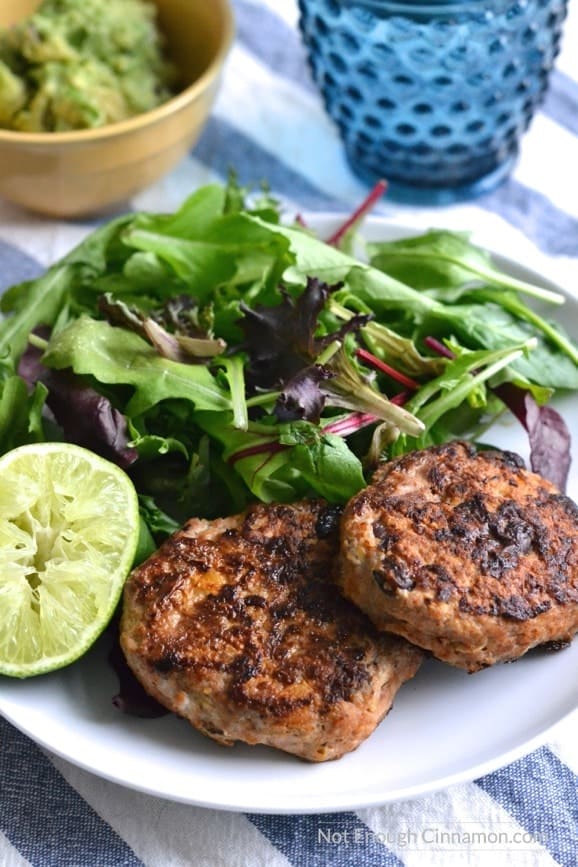 Lean ground chicken patties with sweet corn and black beans on a white plate with a small side salad