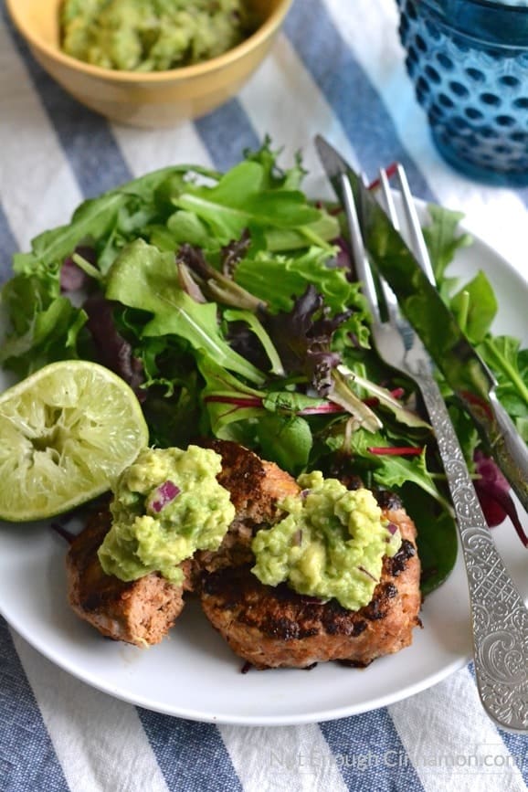 two lean southwestern ground chicken patties smothered with guacamole served alongside a small salad