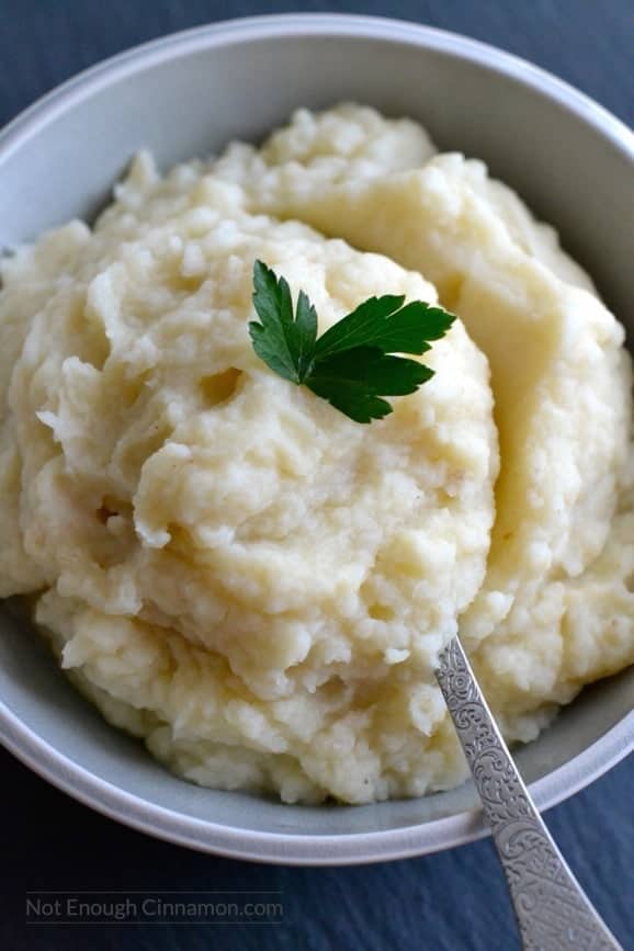 close-up of a bowl of creamy dairy-free celeriac mash topped with a parsley leaf