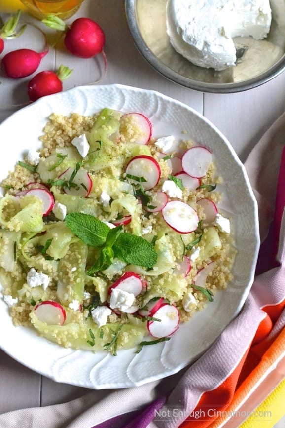 overhead shot of healthy Quinoa Salad with Goats Cheese, Cucumber and Radish slices with a wheel of goat cheese on the side