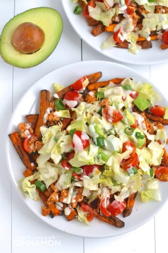 overhead shot of Clean Eating Turkey Taco Loaded Baked Sweet Potato Fries in a white plate with half an avocado on the side 