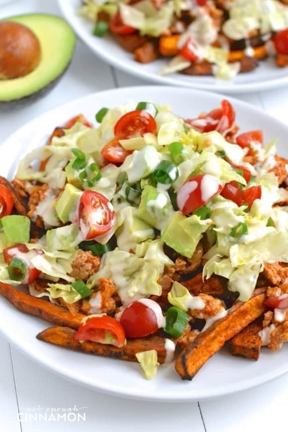 a bowl of baked sweet potato fries topped with taco seasoned ground turkey, homemade salsa and tahini sauce