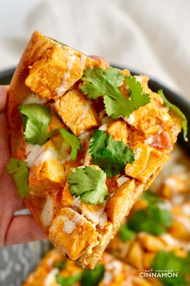a hand holding a slice of Skinny Buffalo Chicken Pizza with gluten-free quinoa crust