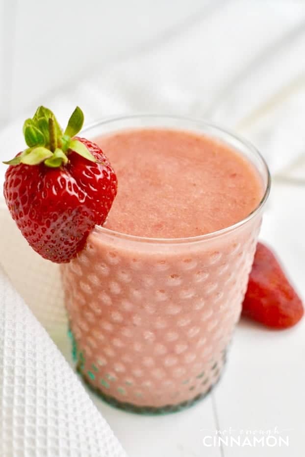 close-up of a glass of strawberry and cantaloupe smoothie with a strawberry as decoration