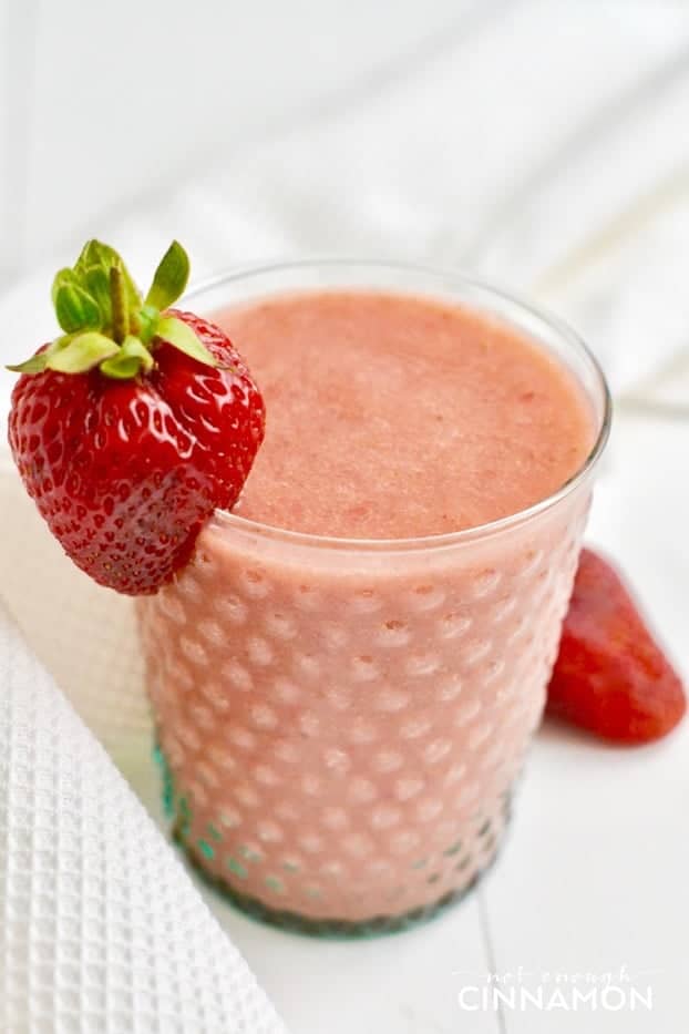 Strawberry and Cantaloupe Smoothie in a tall glass with a strawberry as decoration