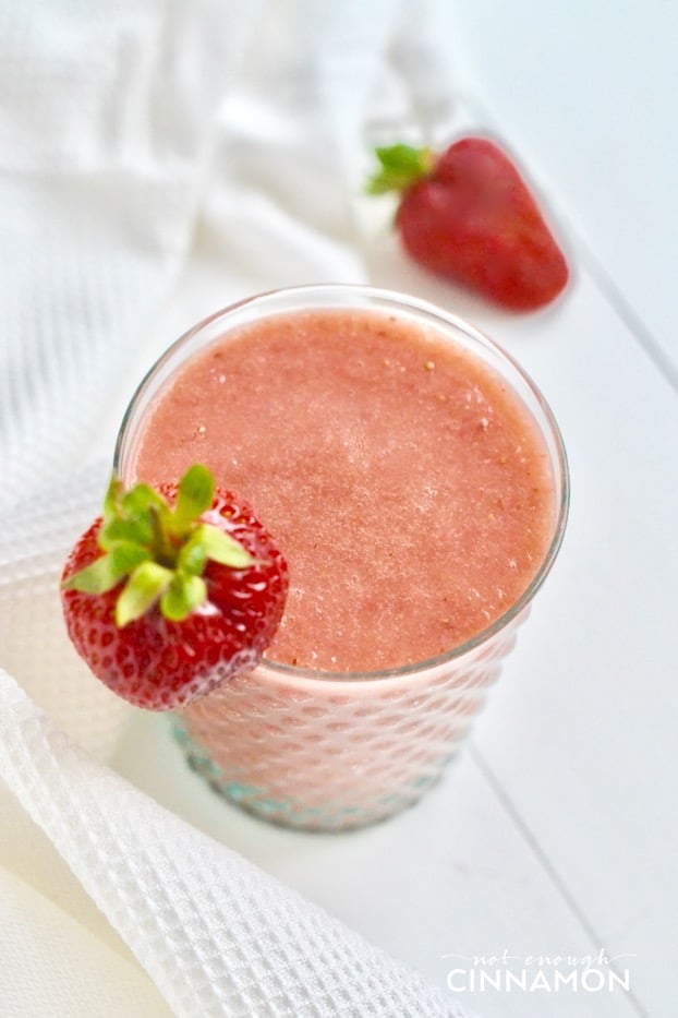 overhead shot of a tall glass of sugar-free strawberry and cantaloupe smoothie with fresh strawberries on the side