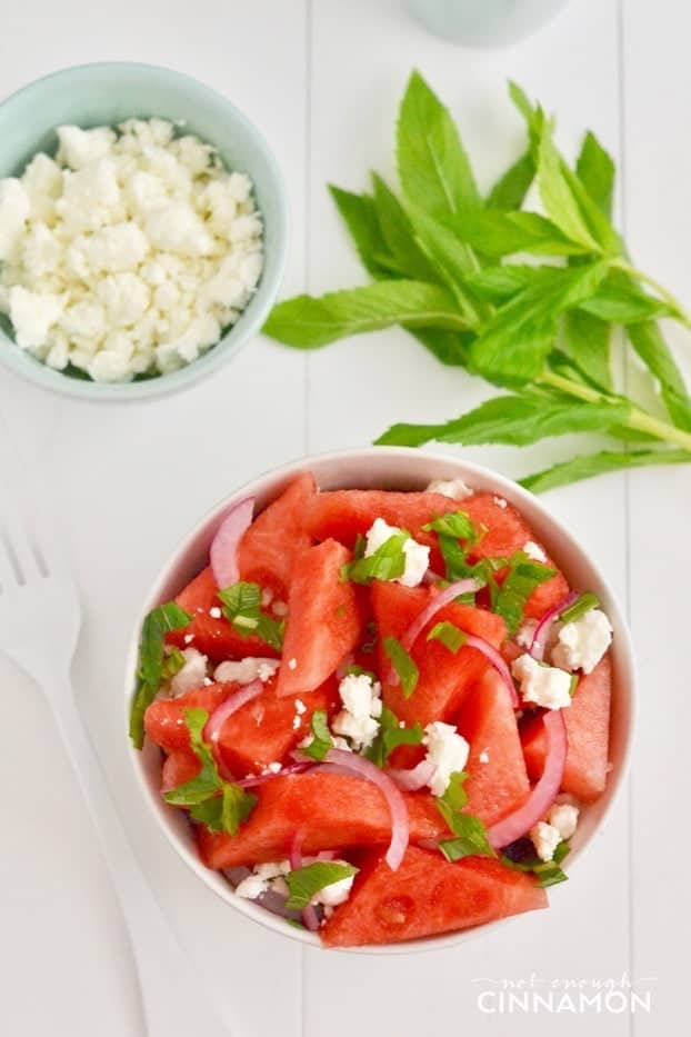 overhead shot of watermelon salad with feta and mint leaves in a white bowl