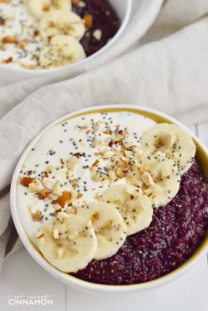 close-up of healthy berry quinoa breakfast bowl topped with Greek yogurt, banana slices and chia seeds