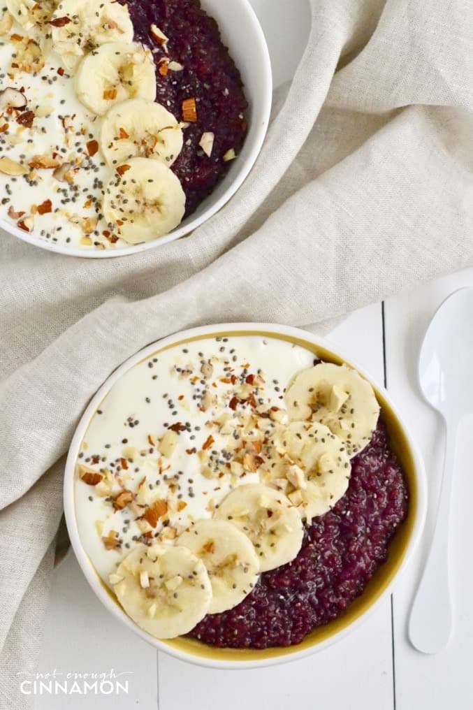 overhead shot of quinoa breakfast bowl with berries, Greek Yogurt, and banana slices