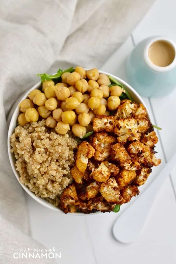 overhead shot of vegan Quinoa Bowl with Roasted Cauliflower, chickpeas and Tahini Dressing on the side