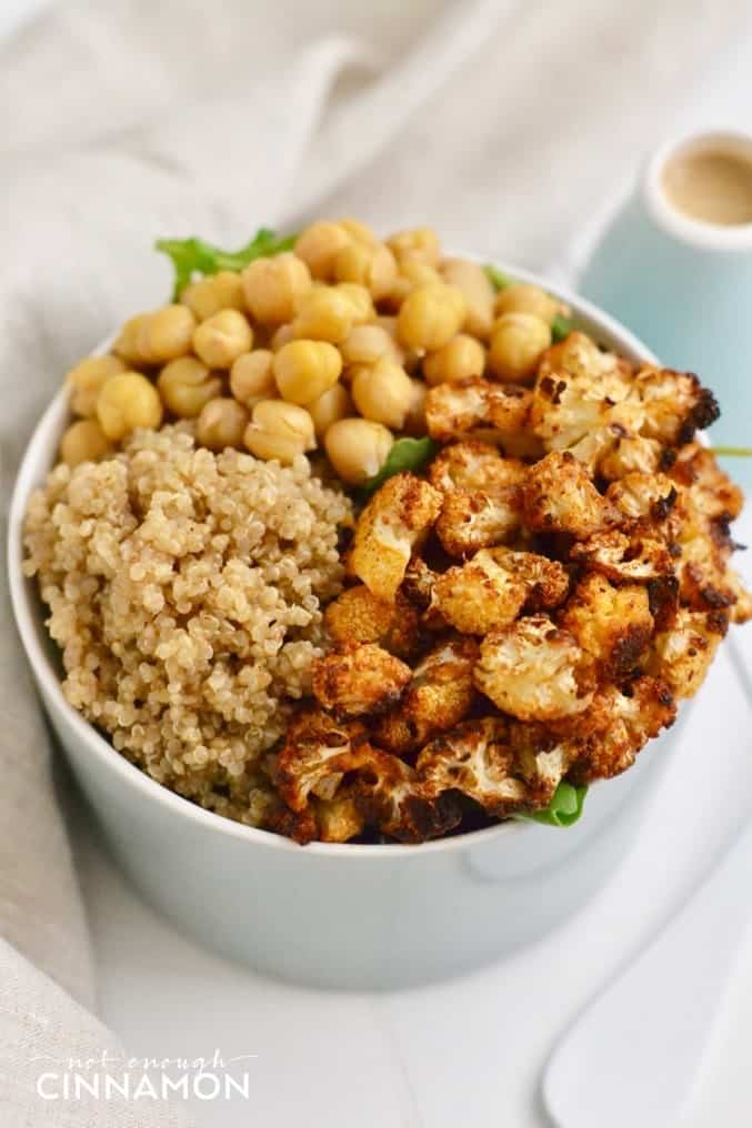 Close-up on a vegan Quinoa Bowl with Roasted Cauliflower, chickpeas and Tahini Dressing on the side