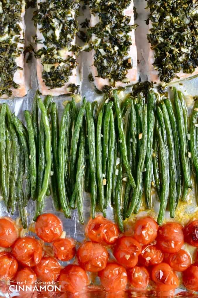 Paleo Sheet Pan Herbed Salmon arranged on a baking sheet with Green Beans and blistered Cherry Tomatoes 