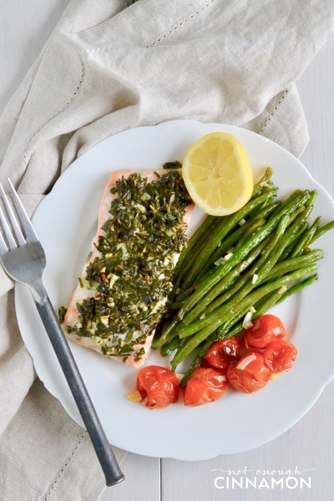 a serving of Paleo Sheet Pan Herbed Salmon served with Green Beans and Cherry Tomatoes on a white plate 