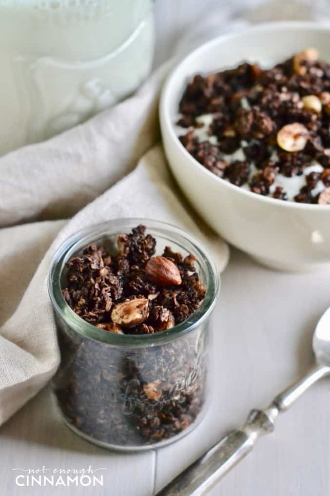 homemade chocolate hazelnut granola in a small glass cup with a spoon on the side