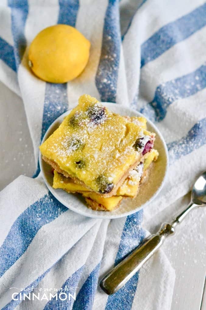 overhead shot of a plate of stacked Blueberry Lemon Bars dusted with icing sugar