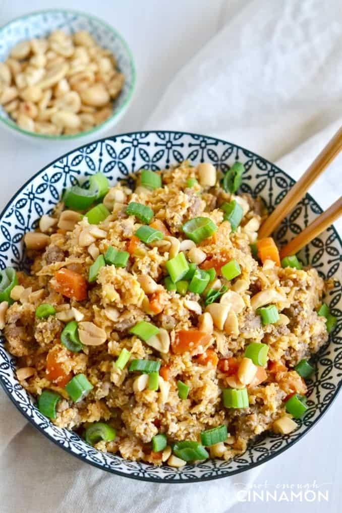 close up on a serving of Asian cauliflower fried rice sprinkled with peanuts and scallions