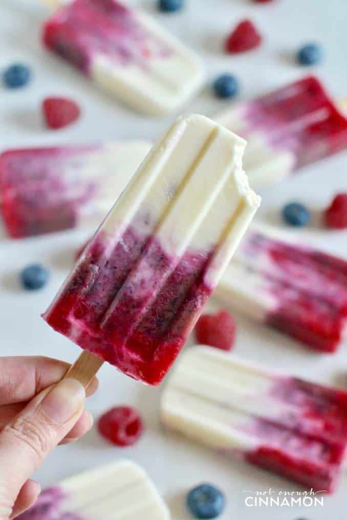 a hand holding a Mixed Berry & Yogurt Popsicle with more popsicles in the background