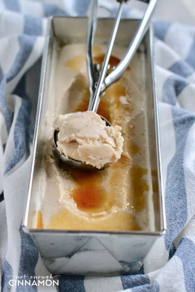 side view of a loaf tin with Banana Cinnamon Greek Yogurt Ice Cream with an ice cream scoop on top