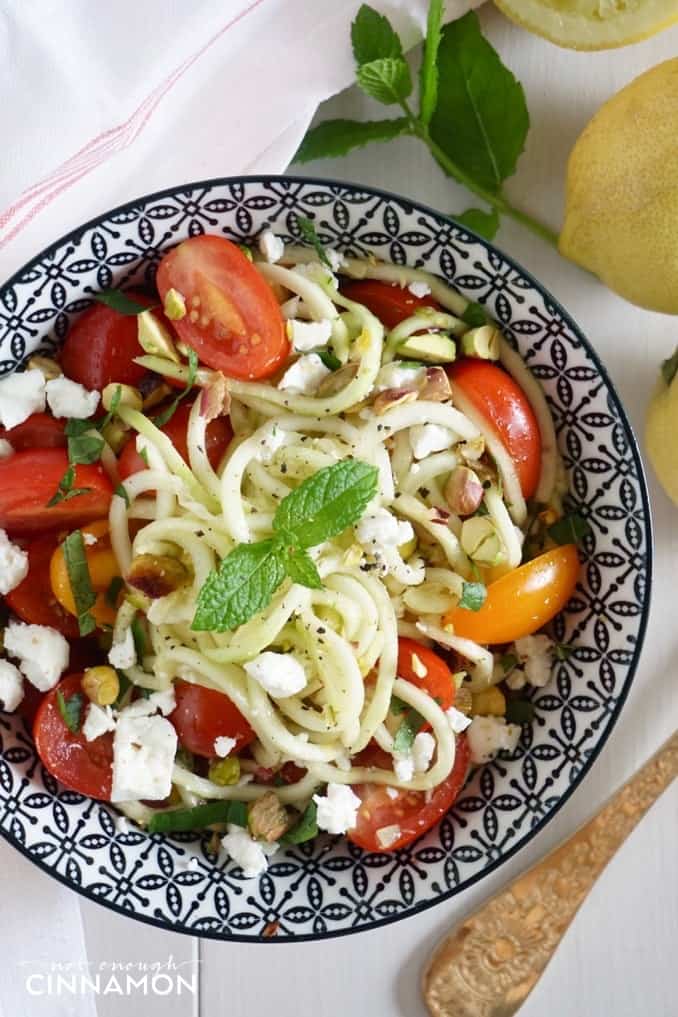 overhead shot of a bowl of zucchini noodle salad with feta, tomatoes and mint 