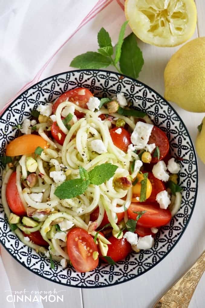 overhead shot of a bowl of low-carb zucchini noodle salad with pistachios, tomatoes and mint