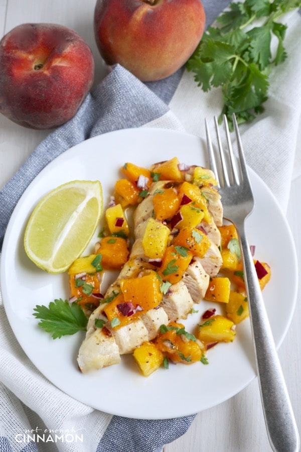 grilled chicken breast topped with mango peach salsa on a white plate