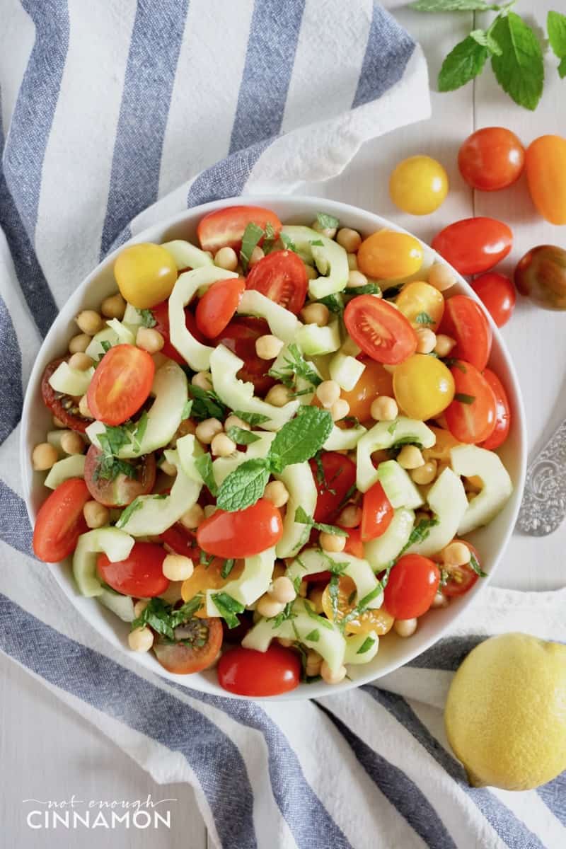 overhead shot of a simple chickpea salad with tomatoes, cucumber and mint in a bowl