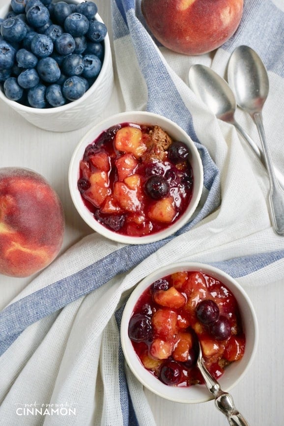 overhead shot of two small ramekins of peach blueberry cobbler