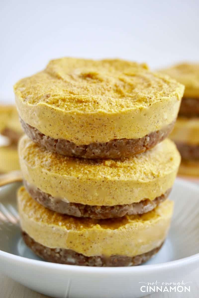 side view of three stacked individual vegan pumpkin cheesecakes on a plate