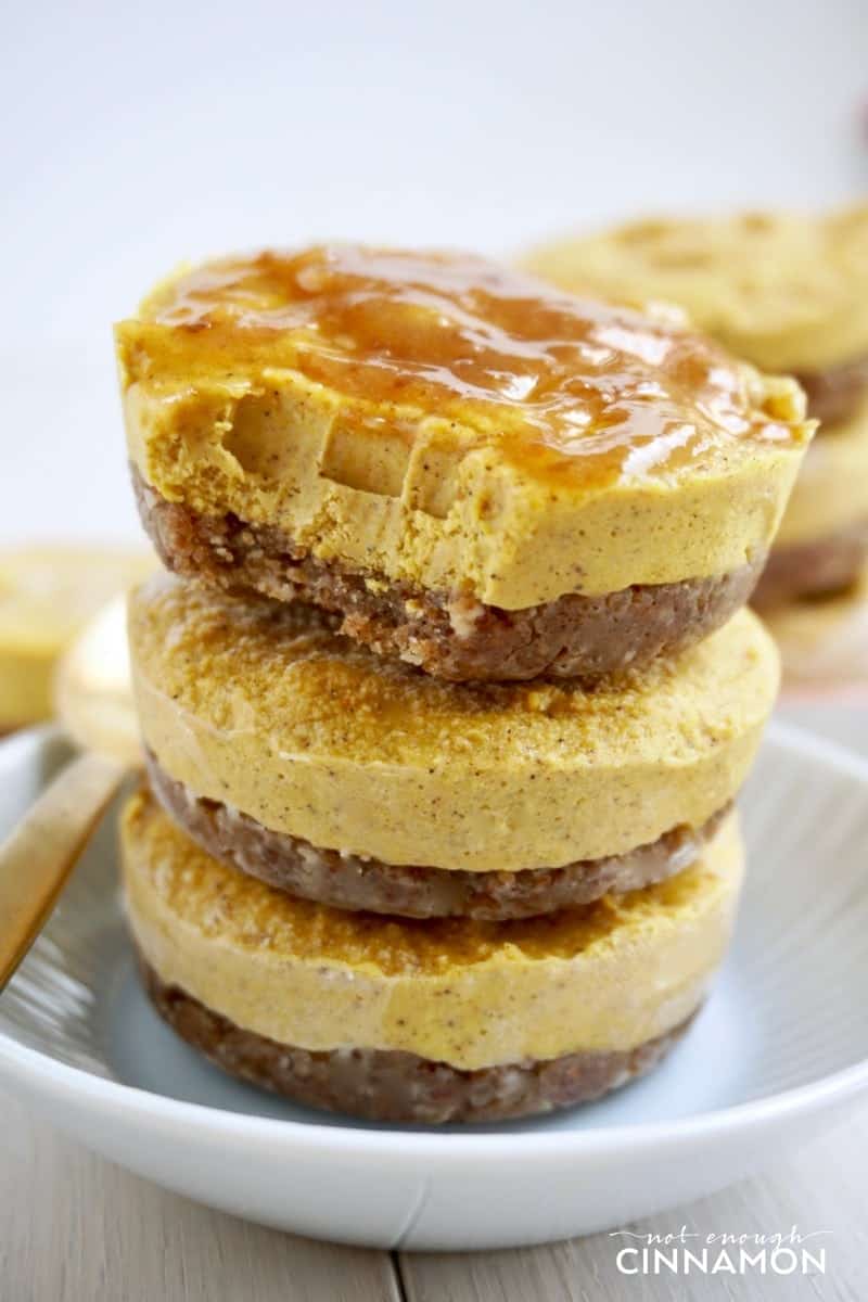 three bite-sized vegan pumpkin cheesecakes stacked on a white plate
